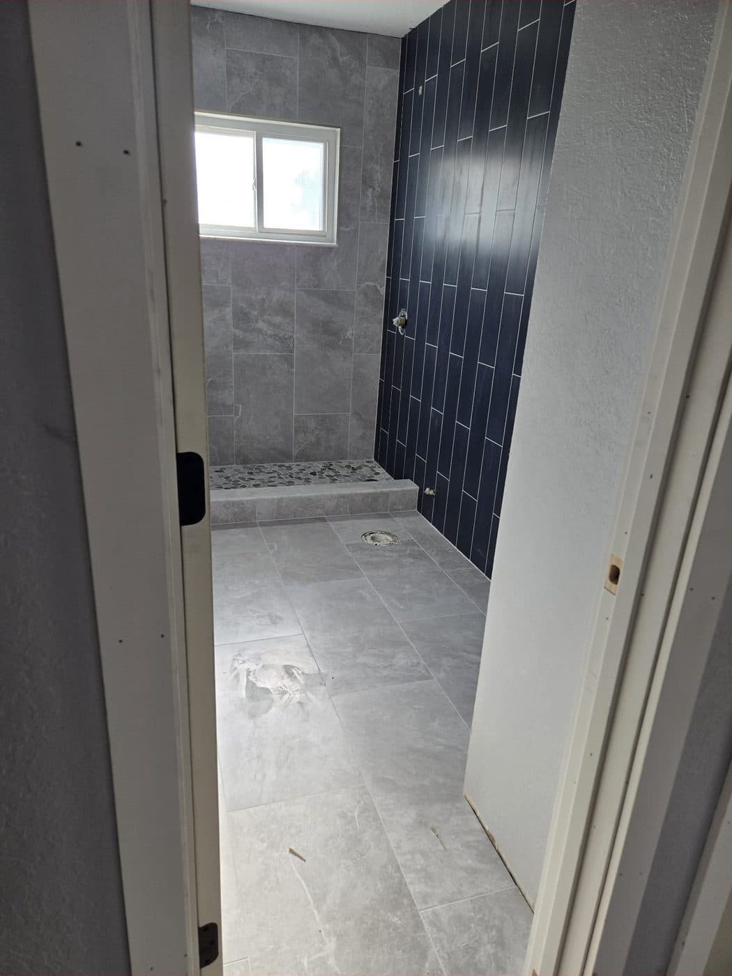 Ducha de porcelanato gris con pared de acento azul marino en patrón vertical — Después